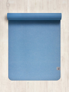 Blue yoga mat partially rolled, eco-friendly material, non-slip texture, top view on wooden floor, fitness accessory, exercise equipment, home workout, wellness and mindfulness concept.