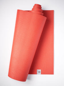 Red textured yoga mat partially rolled with visible brand label, non-slip grip surface, shot from side angle against a white background