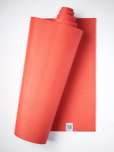 Red textured yoga mat partially rolled up against a white background, side view showing brand logo.
