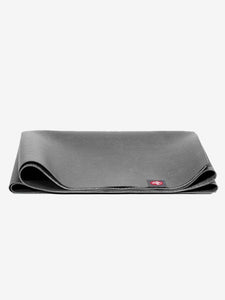 Front shot of a partially rolled dark grey yoga mat with textured surface, visible red logo detail on the corner, exercise accessory for fitness and wellness.