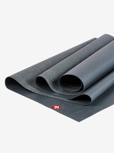 Partially rolled dark grey yoga mat with red logo on corner shot from side angle on a white background