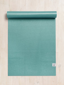 Green textured yoga mat partially rolled up on a wooden floor shot from above.