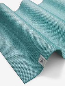 Teal textured non-slip yoga mat with visible brand label from a top angle view.