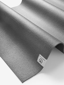 Gray textured yoga mat by Liforme, eco-friendly, side angle view with visible brand logo, non-slip surface, exercise and fitness equipment.
