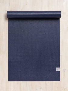Navy blue premium yoga mat partially rolled up with visible brand logo on textured surface, top view on a wooden floor background