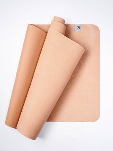 Cork yoga mat rolled up partially, showing textured surface and brand logo on light-colored yoga mat, eco-friendly exercise accessory with natural material, top view on white background.