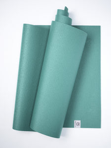 Teal textured yoga mat partially rolled with visible brand logo shot from above against a white background