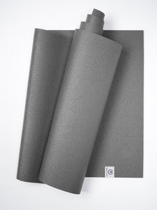 Gray textured yoga mat partially rolled up on a white background, top view, exercise and wellness accessory, non-slip surface design, fitness equipment.