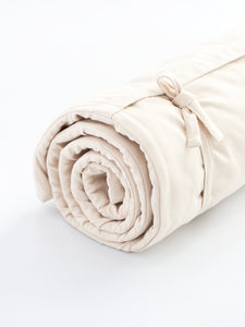 Beige rolled yoga mat side view with strap detail on white background