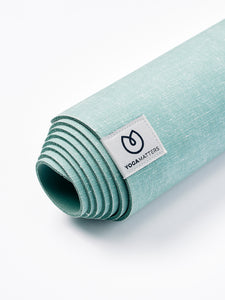 Close-up side view of a teal green YOGAMATTERS yoga mat rolled up on a white background