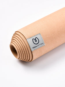 Yogamatters rolled-up beige yoga mat shot from side on white background showing texture and brand label