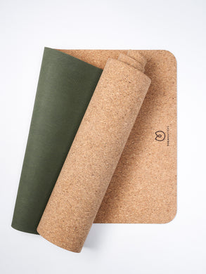 Eco-friendly cork yoga mat with green overlay, rolled and unrolled yoga mats side view on white background.