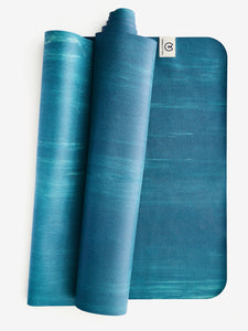 Blue gradient yoga mat partially rolled, textured eco-friendly material, non-slip exercise mat, front view with visible brand logo, fitness and wellness equipment.