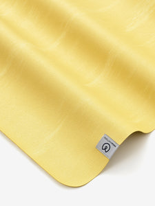 Yellow textured yoga mat by Lululemon positioned diagonally with brand label visible, high-quality non-slip surface, close-up view from above.