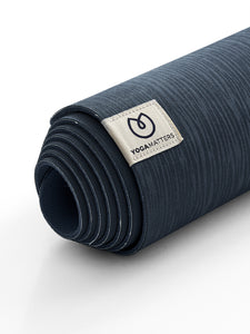 Dark blue textured YOGAMATTERS yoga mat rolled up, side view with brand label visible on white background