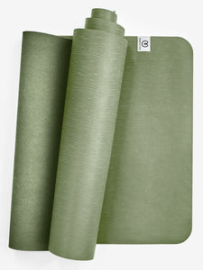 Green textured yoga mat partially rolled with visible brand tag on top right, eco-friendly non-slip exercise mat, front view, studio shot for fitness and wellness.