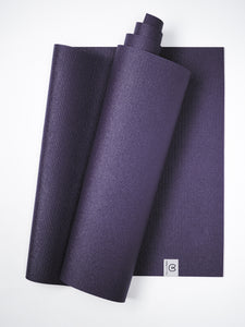 Purple textured yoga mat partially rolled, top view, non-slip grip surface, fitness and wellness accessory, visible brand logo.