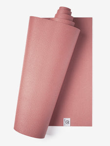 Pink textured yoga mat partially rolled with logo visible in a vertical top-down view.