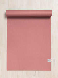 Top-view image of partially rolled coral yoga mat on a wooden floor, textured non-slip surface, eco-friendly exercise mat for yoga and Pilates.