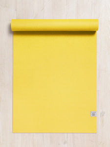 Bright yellow textured yoga mat partially rolled up at the top on a wooden floor, top view, with visible brand tag