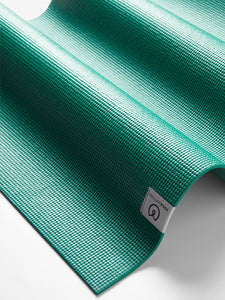 Teal textured non-slip yoga mat by Lululemon, close-up side view showing brand label, ideal for fitness and meditation.