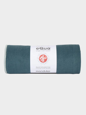 eQua Manduka yoga mat towel in teal color, front view, sweat-activated grip, ultra plush, super absorbent, rolled up, with visible logo and text details.