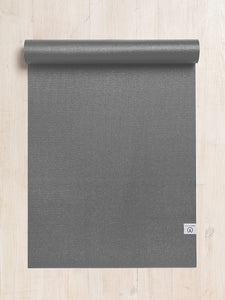 Gray textured yoga mat partially rolled up with visible Lululemon logo on wooden floor, top-down view.