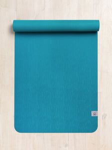 Teal yoga mat partially rolled up on a wooden floor, textured non-slip surface, top view