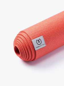 Coral textured YogaMatters yoga mat rolled up side view on white background
