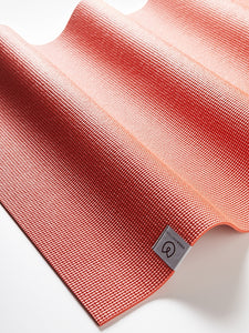 Red textured yoga mat by Lululemon, close-up shot of wavy edge design and non-slip surface, shot from side angle with visible logo.