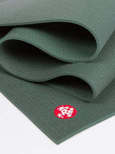 Green textured yoga mat partially rolled with visible logo, close-up side view showing non-slip surface detail.