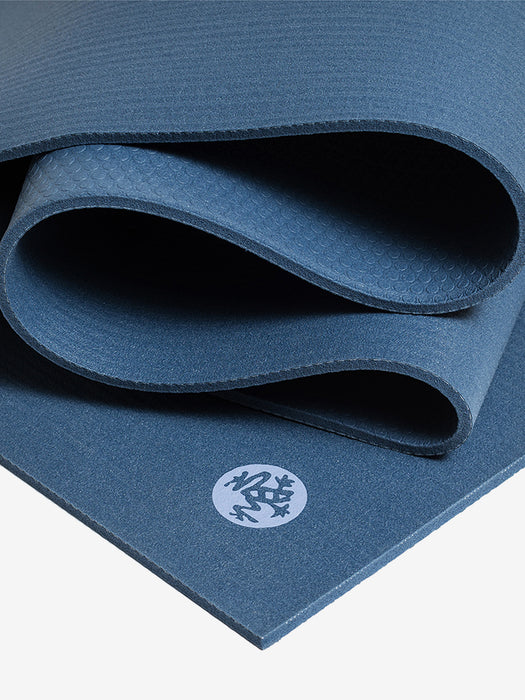 Navy blue textured yoga mat partially rolled with visible brand logo, close-up side view for fitness and meditation.