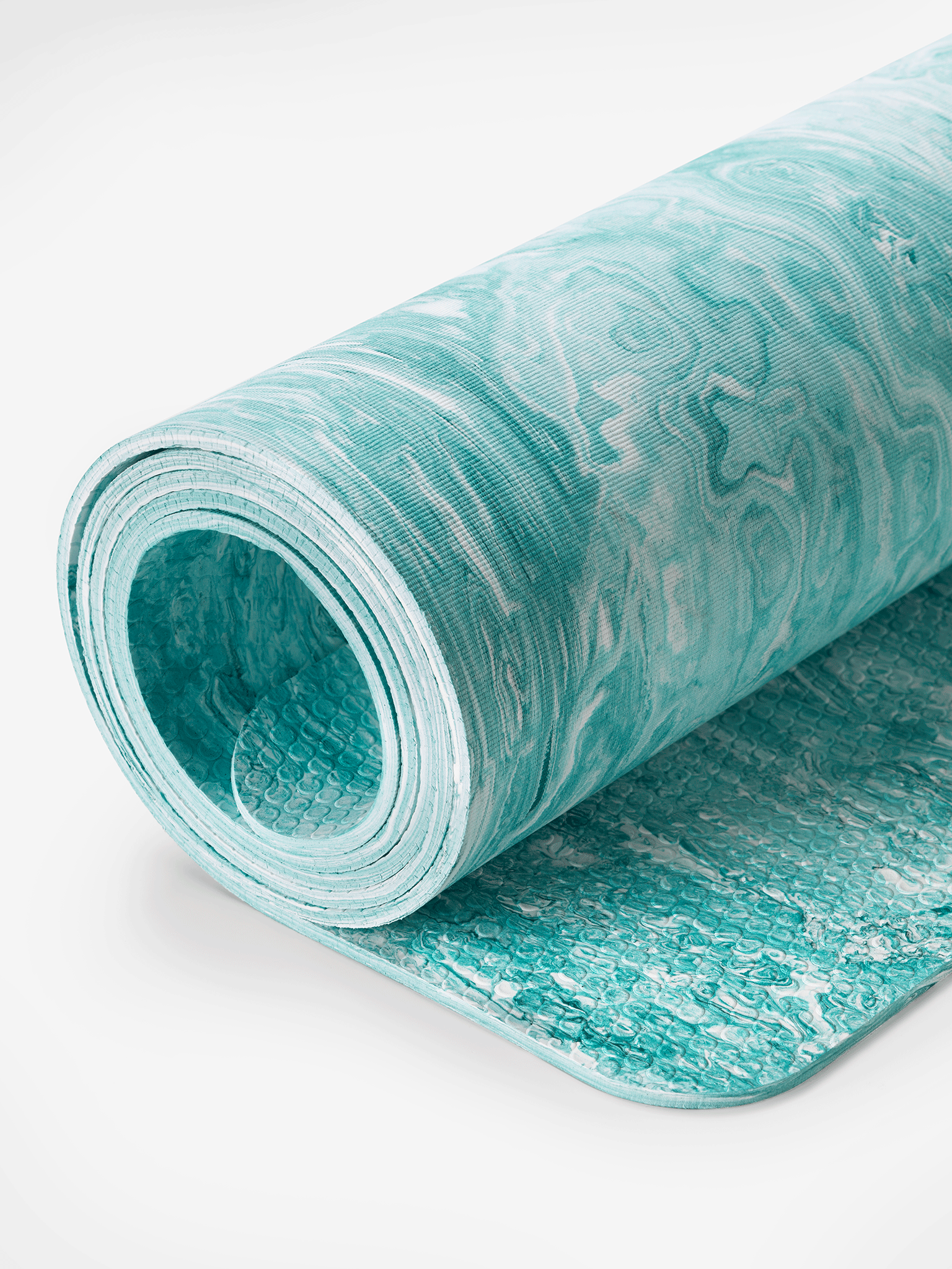 Textured blue yoga mat partially rolled up on a white background showing non-slip surface detail, side view.