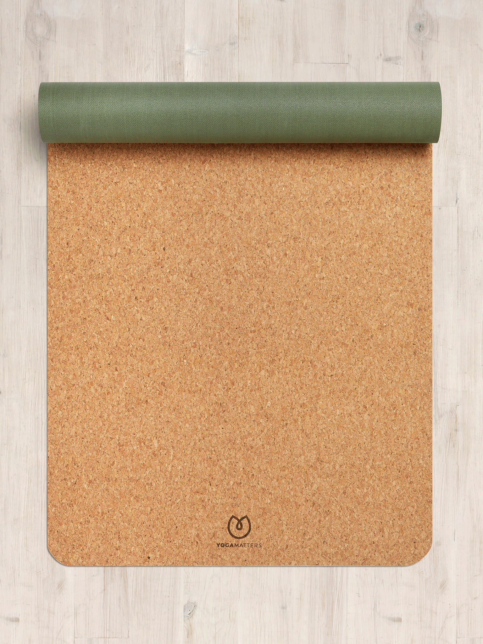 Eco-friendly cork yoga mat by Yogamatters, partially rolled olive green and natural cork color, top view on light wooden floor background, durable and sustainable yoga accessory for fitness and wellness.