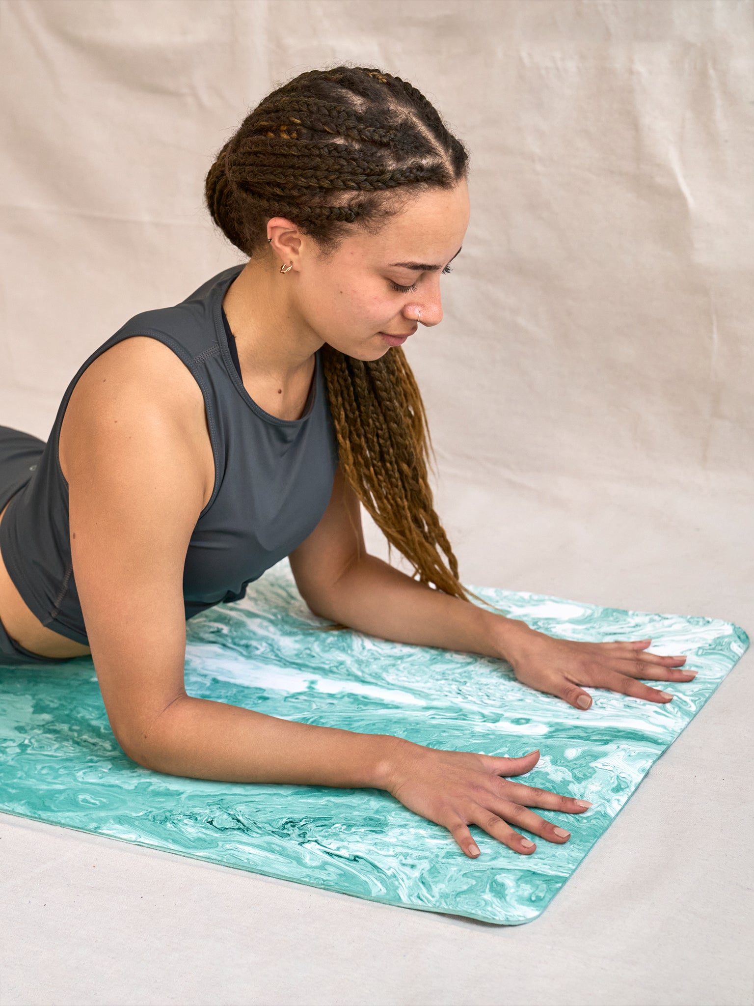 Woman practicing yoga on a turquoise marbled-pattern yoga mat, side angle view, fitness and wellness concept.