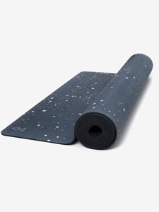 Premium dark blue yoga mat with white speckled pattern partially rolled up, eco-friendly non-slip material, side angle view showing thickness and textured surface detailing.