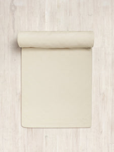 Beige yoga mat partially rolled out on a wooden floor with a visible logo, top view, high-quality non-slip exercise mat for fitness and meditation