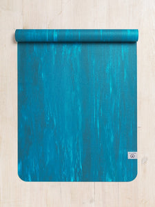 Teal yoga mat rolled up at top on wooden floor, non-slip textured surface, eco-friendly material, top view, exercise and fitness equipment
