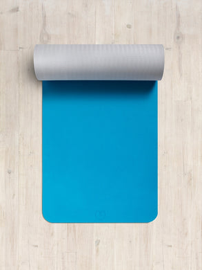 Blue yoga mat partially rolled up on a wooden floor, non-slip texture, exercise and fitness equipment, top view