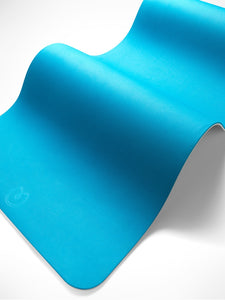 Blue textured yoga mat with brand logo visible, angled side view, showing detail of thickness and surface pattern.