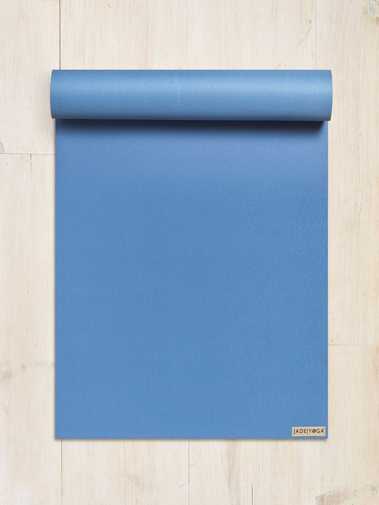Blue JadeYoga mat rolled up partially on a light wooden floor, top view, fitness and wellness concept