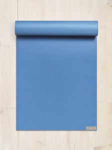 Blue JadeYoga mat rolled up partially on a light wooden floor, top view, fitness and wellness concept
