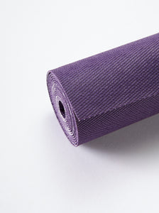 Close-up of rolled-up purple yoga mat on a white background, texture visible, non-slip surface, exercise equipment, fitness accessory, side view.