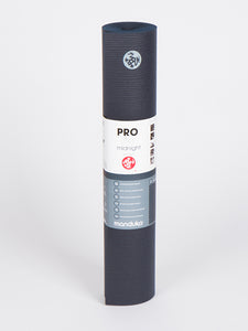 Manduka PROlite yoga mat in midnight color, rolled up, front view on a white background, textured, professional quality, eco-friendly, non-slip surface.