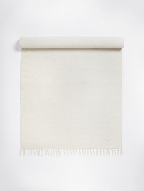 Beige eco-friendly yoga mat with tassels and subtle brand logo, front view on a white background.