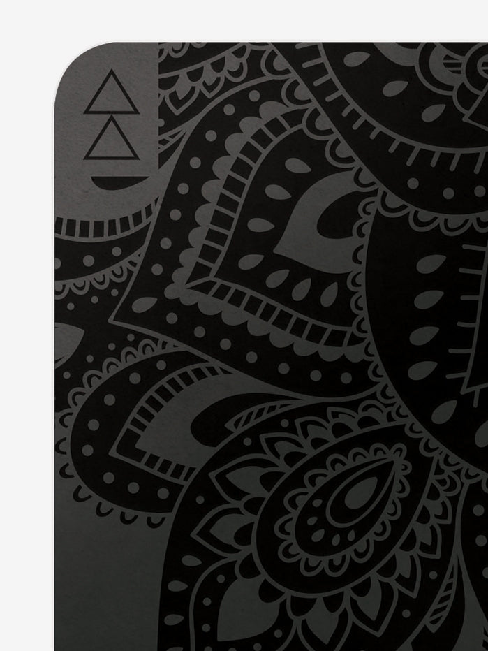 Black yoga mat with mandala pattern, eco-friendly non-slip surface, close-up side angle view, fitness and wellness accessory.