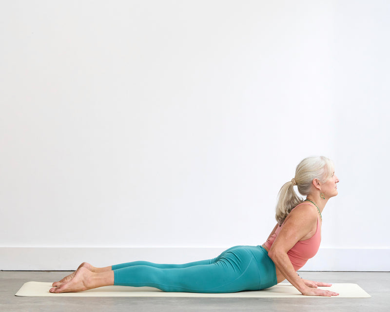 Person practising Cobra Pose (Bhujangasana), lying on the front with the hands grounded beneath the shoulders and the chest gently lifted into a backbend.
