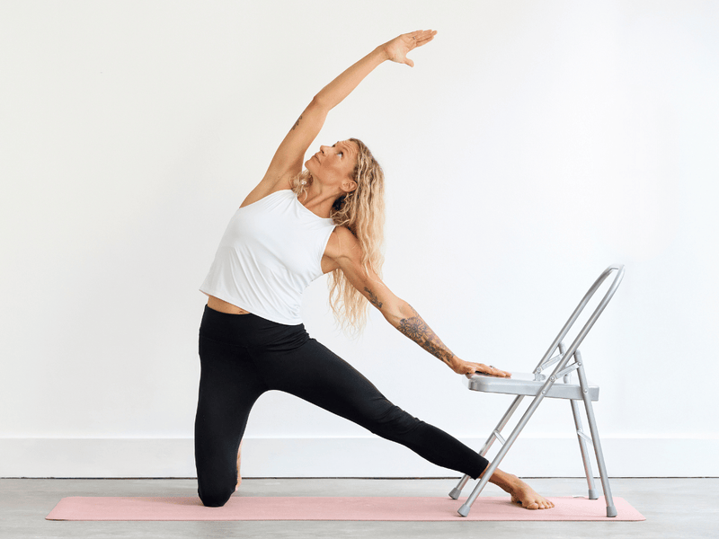 Person practising Gate Pose (Parighasana) using a yoga chair for support.