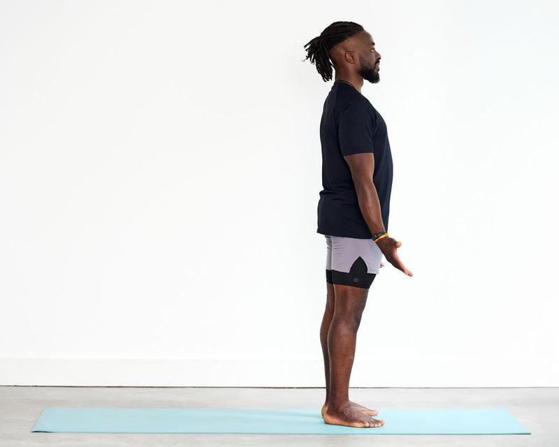 Person practising Mountain Pose (Tadasana), standing upright with feet grounded, arms relaxed alongside the body and spine lengthened.