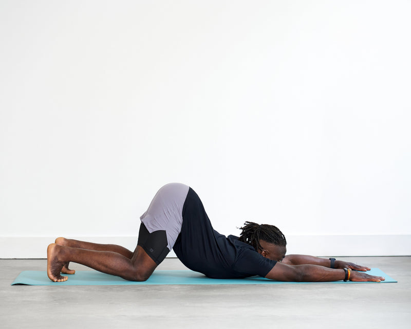 Person practising Puppy Pose (Uttana Shishosana), kneeling with hips lifted above the knees and arms extended forward as the chest lowers towards the floor.